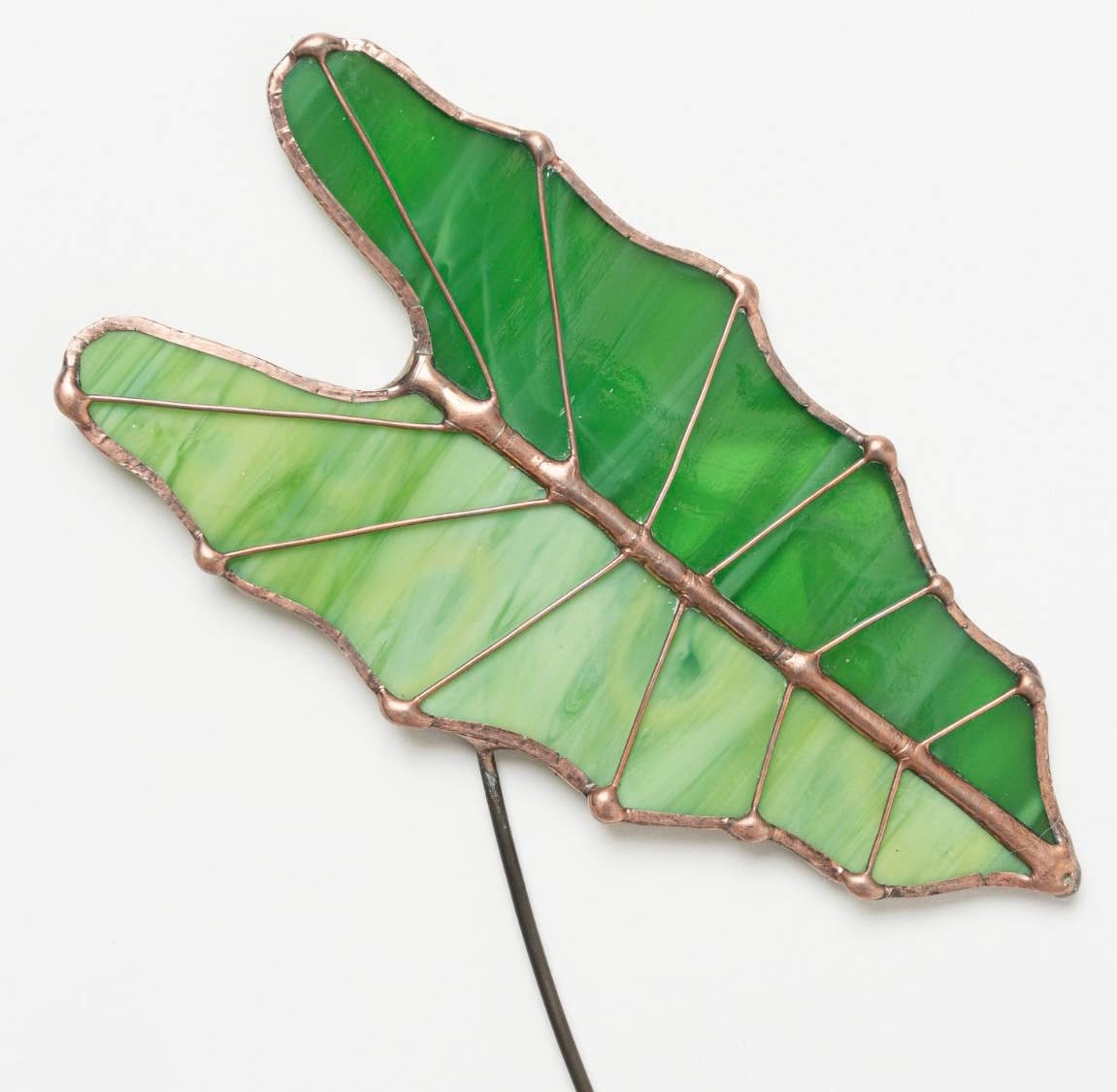 Green stained glass Alocasia leaf with copper-colored seams on a wire stem
