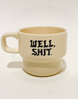 Beige mug with 'WELL, SHIT.' text on a white background