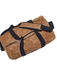 Tan waxed canvas duffel bag from above, showing the padded handle wrap and side zip pocket