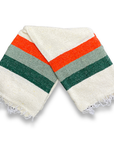 Cream Sea Breeze blanket with green, sage and orange stripes, folded in half on a white background