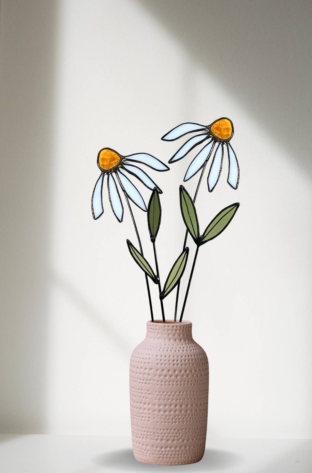 Pale blue and white stained glass coneflower stems in a pink textured vase