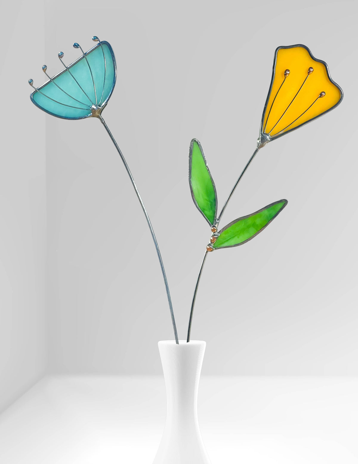 Stained glass yellow tulip and aqua flower stems in a white bud vase