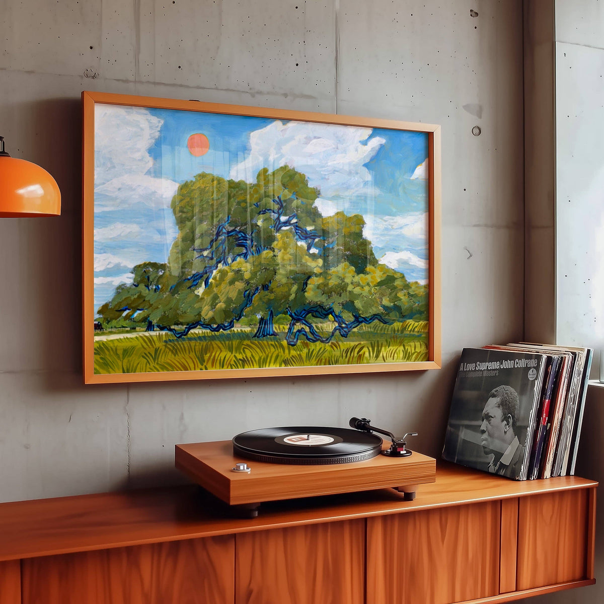 Live oak art print in a wood frame on a concrete wall above a console with a turntable and records