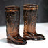 Pair of brown glass cowboy boot shot glasses on a white surface with a dark background