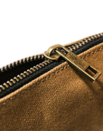 Close-up of a brass zipper pull on tan waxed canvas, slightly unzipped