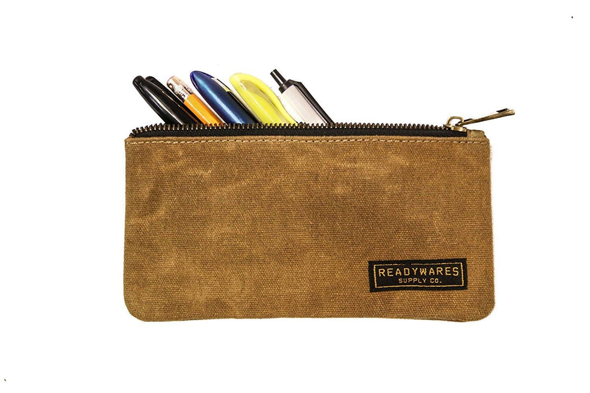 Tan waxed canvas zip pouch holding pens and pencils on a white background