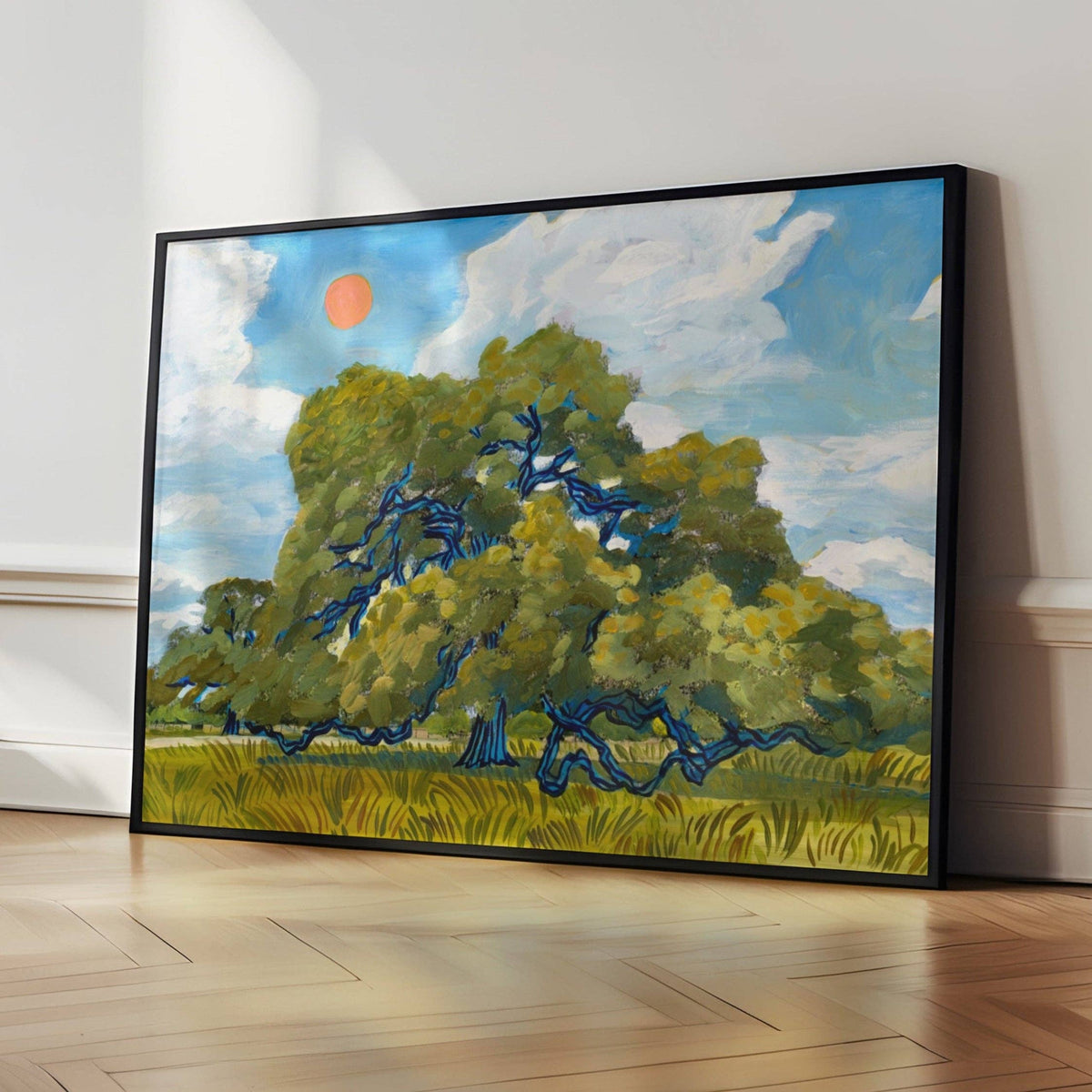 Large black-framed live oak print leaning on a wood floor against a white wall