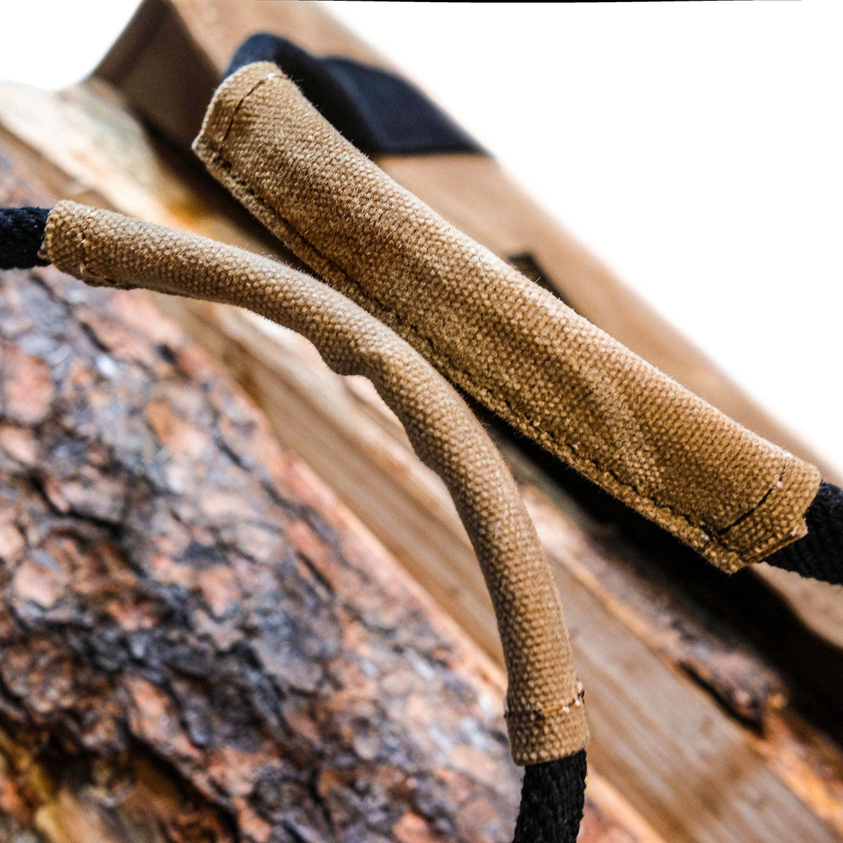 Close-up of the waxed canvas handle wraps resting on a log