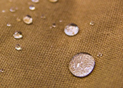 Close-up of water beading on tan waxed canvas