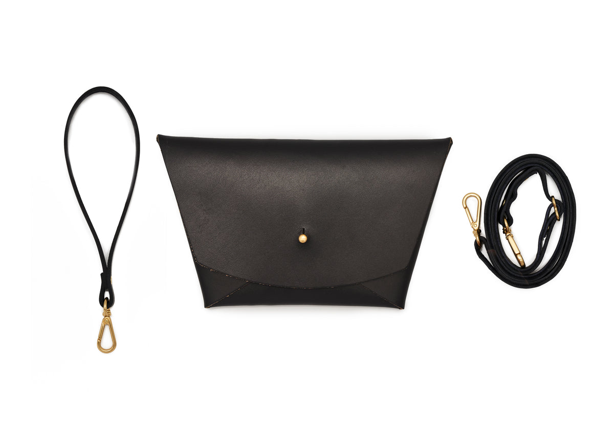 Black leather clutch with wrist strap and adjustable crossbody strap on white